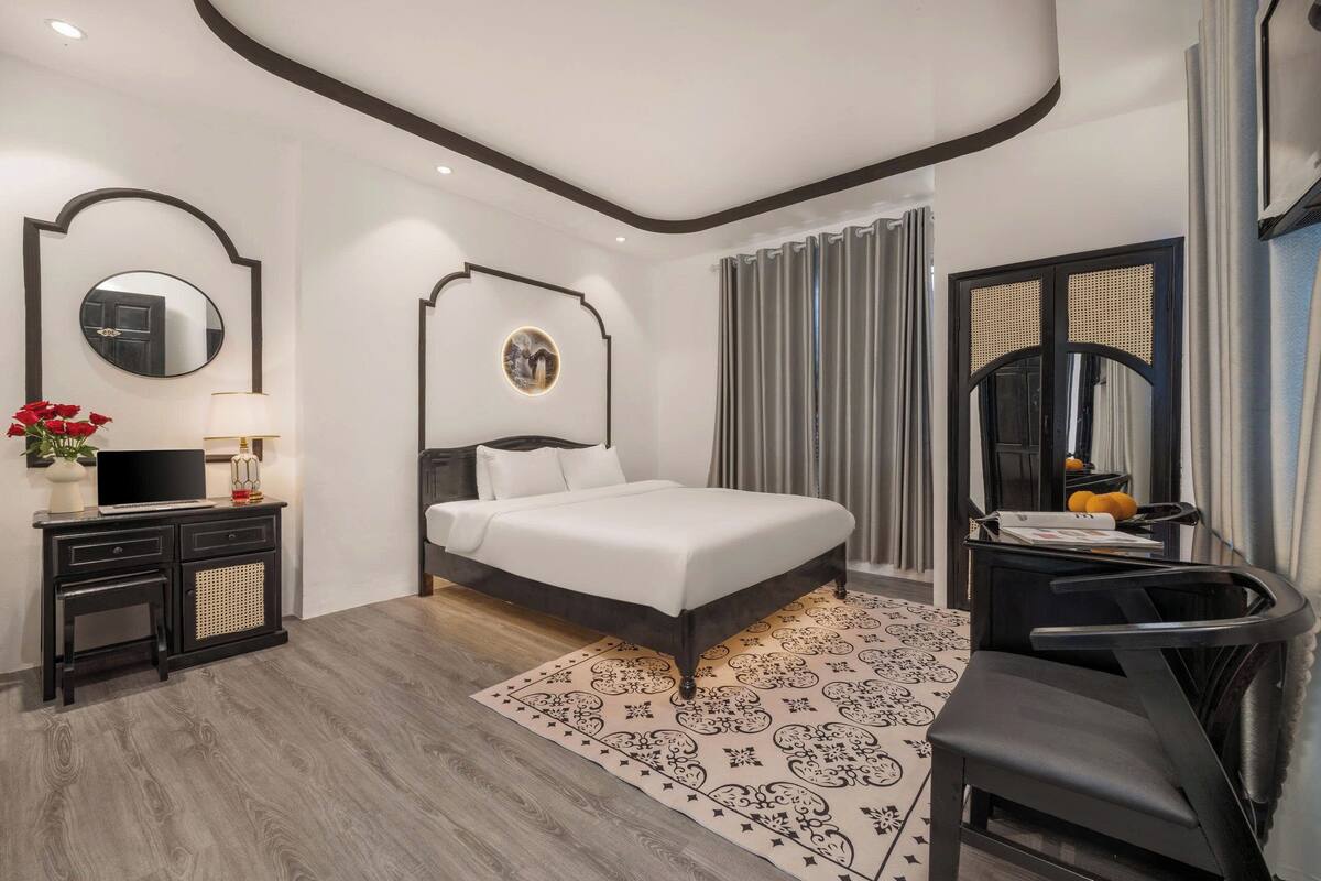 Une chambre moderne avec un grand lit, un bureau, une chaise et un téléviseur.