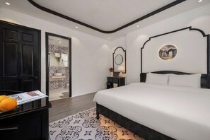 A modern hotel room with a large bed, a nightstand, a mirror, and a door leading to a bathroom. - De Huong Duong residences (Hue)