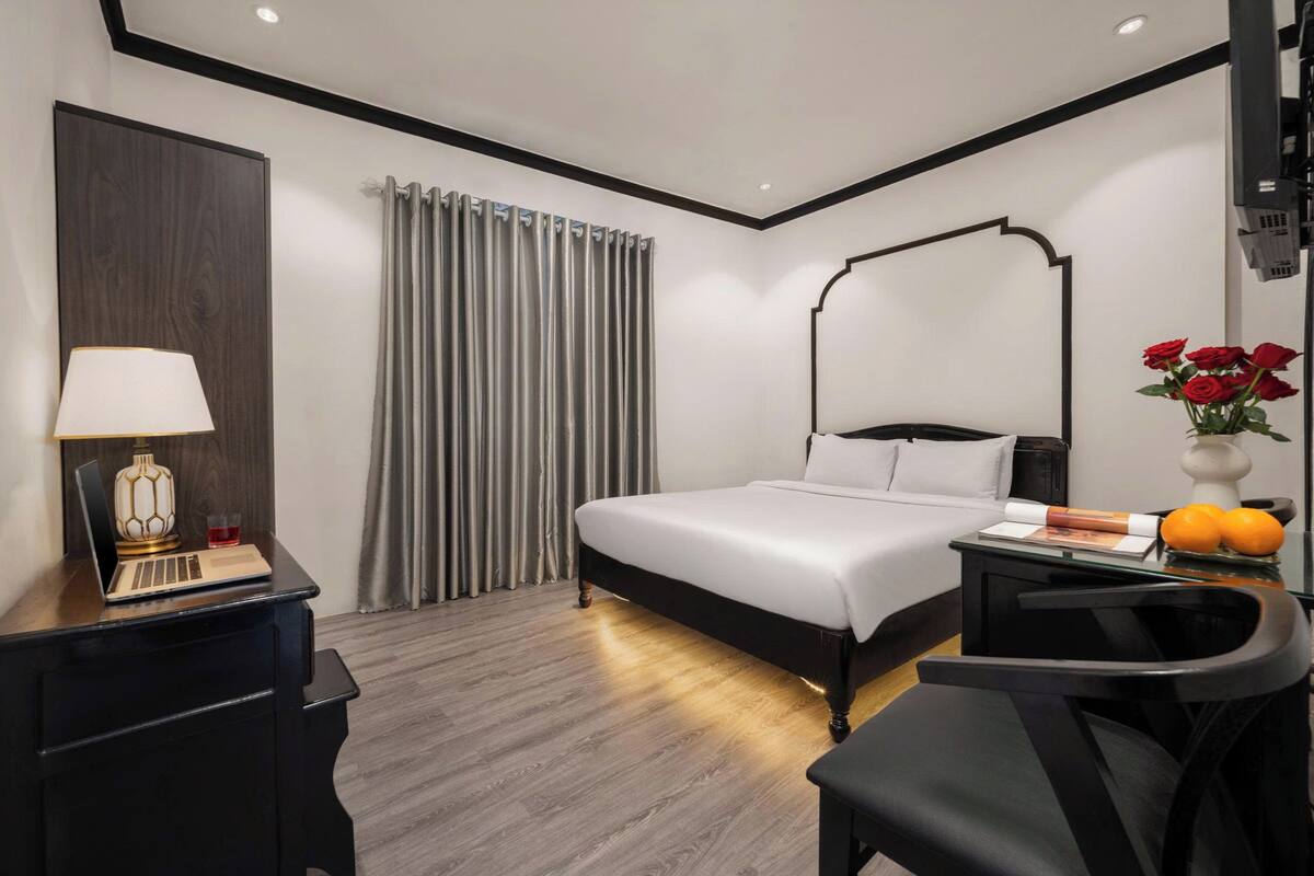 Une chambre d’hôtel moderne équipée d’un lit, d’un bureau, d’une chaise et d’une lampe de bureau.