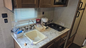 A compact kitchen with a sink, a coffee maker, and a stove. - Adventurer, RV in delightful Atlanta with AC (Atlanta)