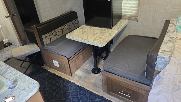 A compact RV interior with a bed, a small kitchenette, and a seating area. - Adventurer, RV in delightful Atlanta with AC (Atlanta)