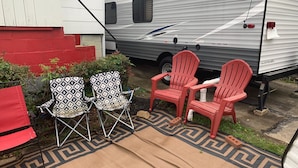A caravan parked outside a house with two folding chairs and a red chair in front. - Adventurer, RV in delightful Atlanta with AC (Atlanta)