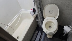 A bathroom with a bathtub, toilet, and a hand dryer. - Adventurer, RV in delightful Atlanta with AC (Atlanta)