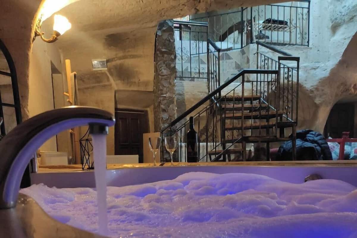 Ein Whirlpool mit fließendem Wasserhahn, eine Treppe mit Metallgeländer und eine Steinwand im Hintergrund.