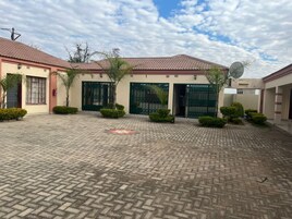 Un patio con un camino empedrado, un edificio con techo de tejas y una antena parabólica.