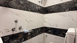 Et badeværelse med toilet, bidet og en stor blå spand.