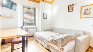 Une pièce avec un plafond en bois, un lit recouvert d’une couverture à motifs, une table avec des chaises et une fenêtre donnant sur le ciel.