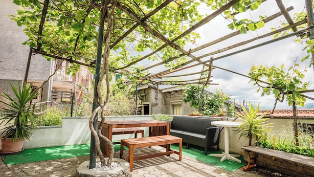 Une terrasse extérieure avec une table et un banc en bois, un canapé et des plantes en pot.