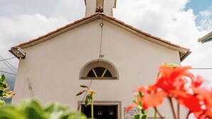 Un bâtiment blanc avec un toit recouvert de tuiles rouges et une petite fenêtre en arc de cercle.
