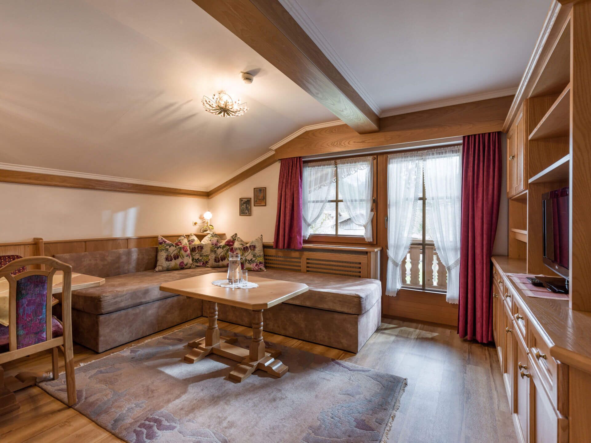 Een gezellige woonkamer met een houten bank, een bank, een tafel en een televisie.