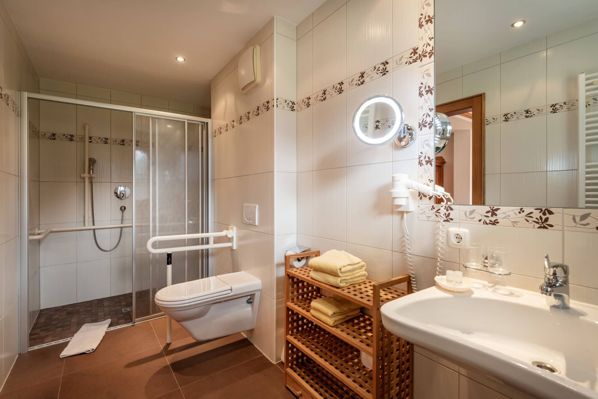 A modern bathroom with a glass shower enclosure, a toilet, a vanity with a sink and mirror, and a towel rack.