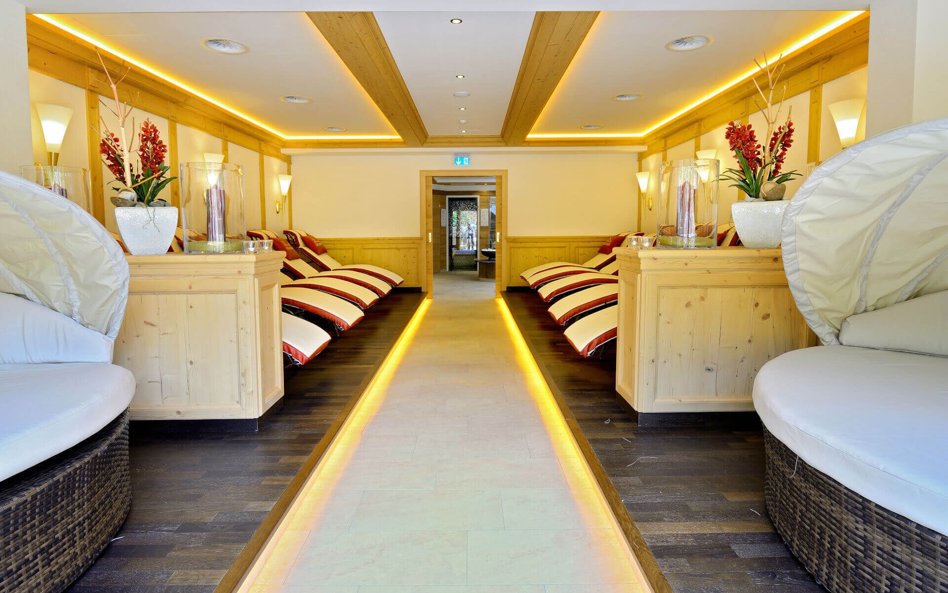 A spa room with a central pathway, wooden paneling, and massage chairs.