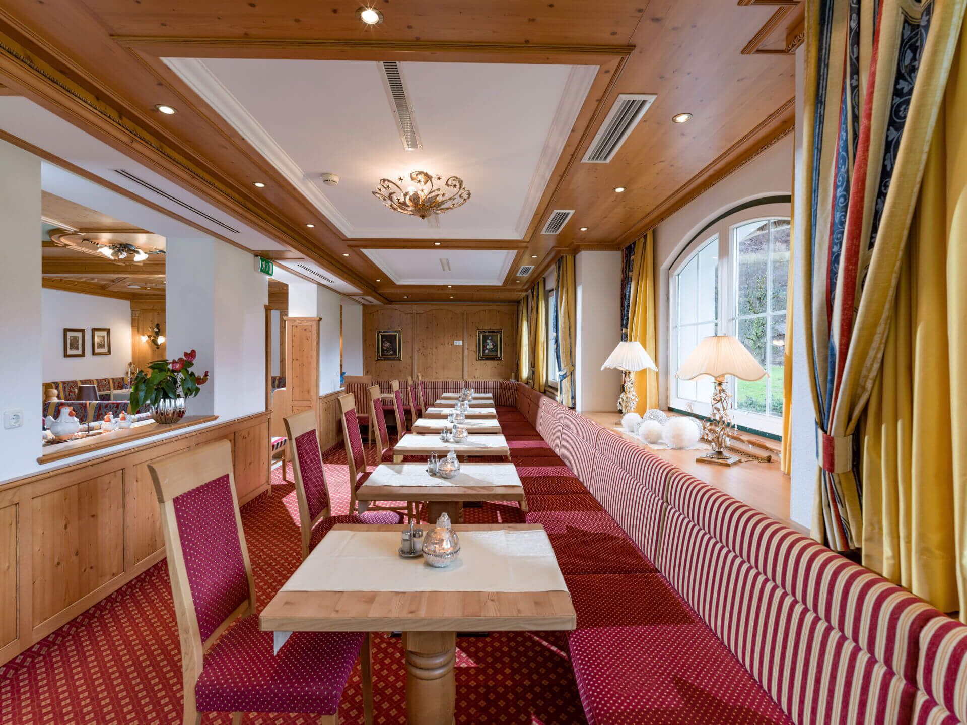 A long dining table with benches, wooden paneling, and a chandelier.
