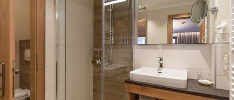A modern bathroom with a glass-enclosed shower, a white sink, and a mirror above it.