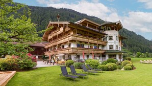A traditional Alpine-style building with multiple balconies, a well-maintained lawn, and outdoor seating. - Ferienhof Oblasser (Mayrhofen)