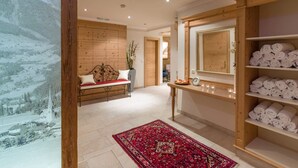 A hotel room with a wooden bench, a large mirror, and shelves with towels. - Ferienhof Oblasser (Mayrhofen)