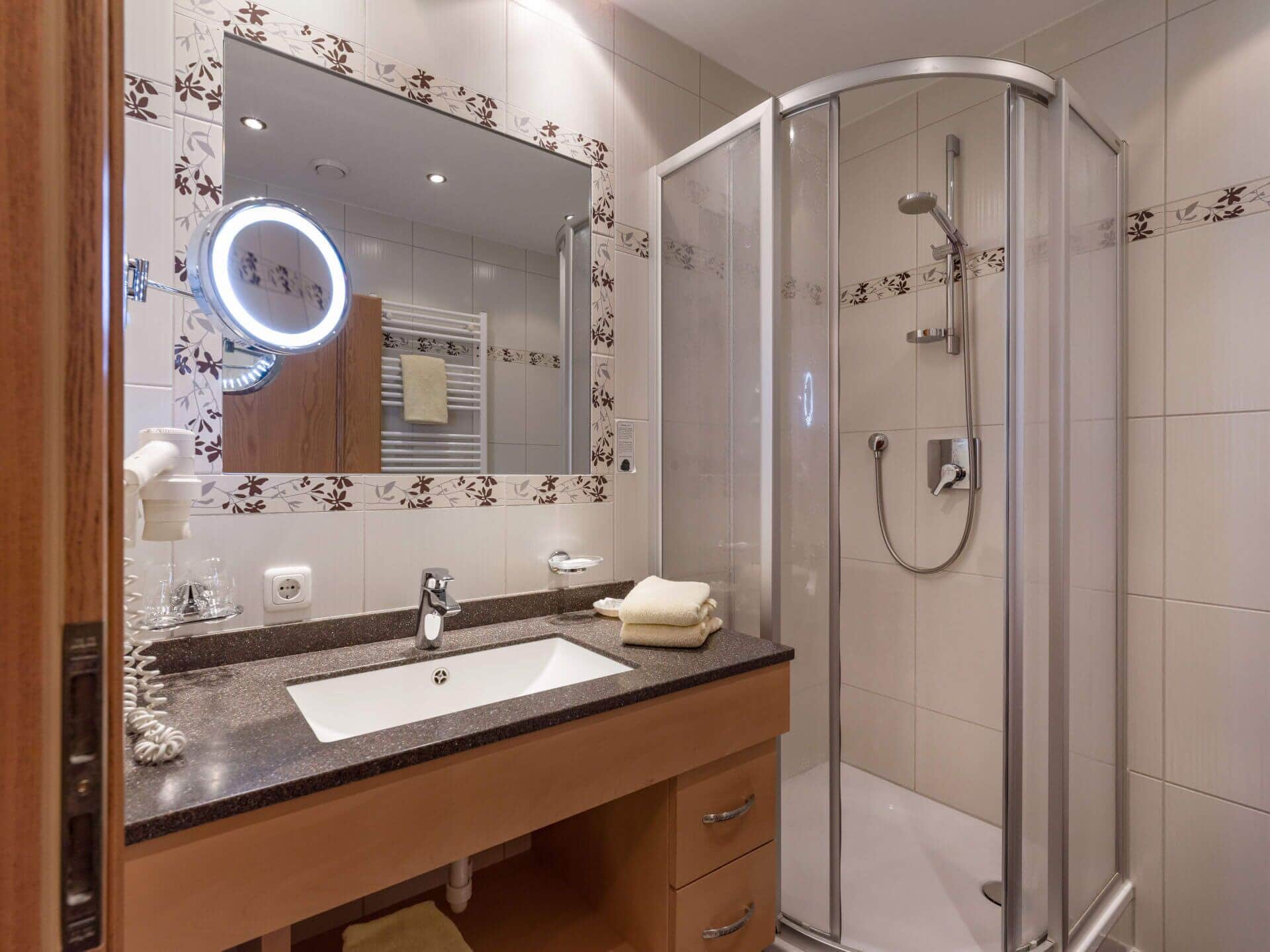 A modern bathroom with a curved shower, a vanity with a sink, and a mirror with a light.