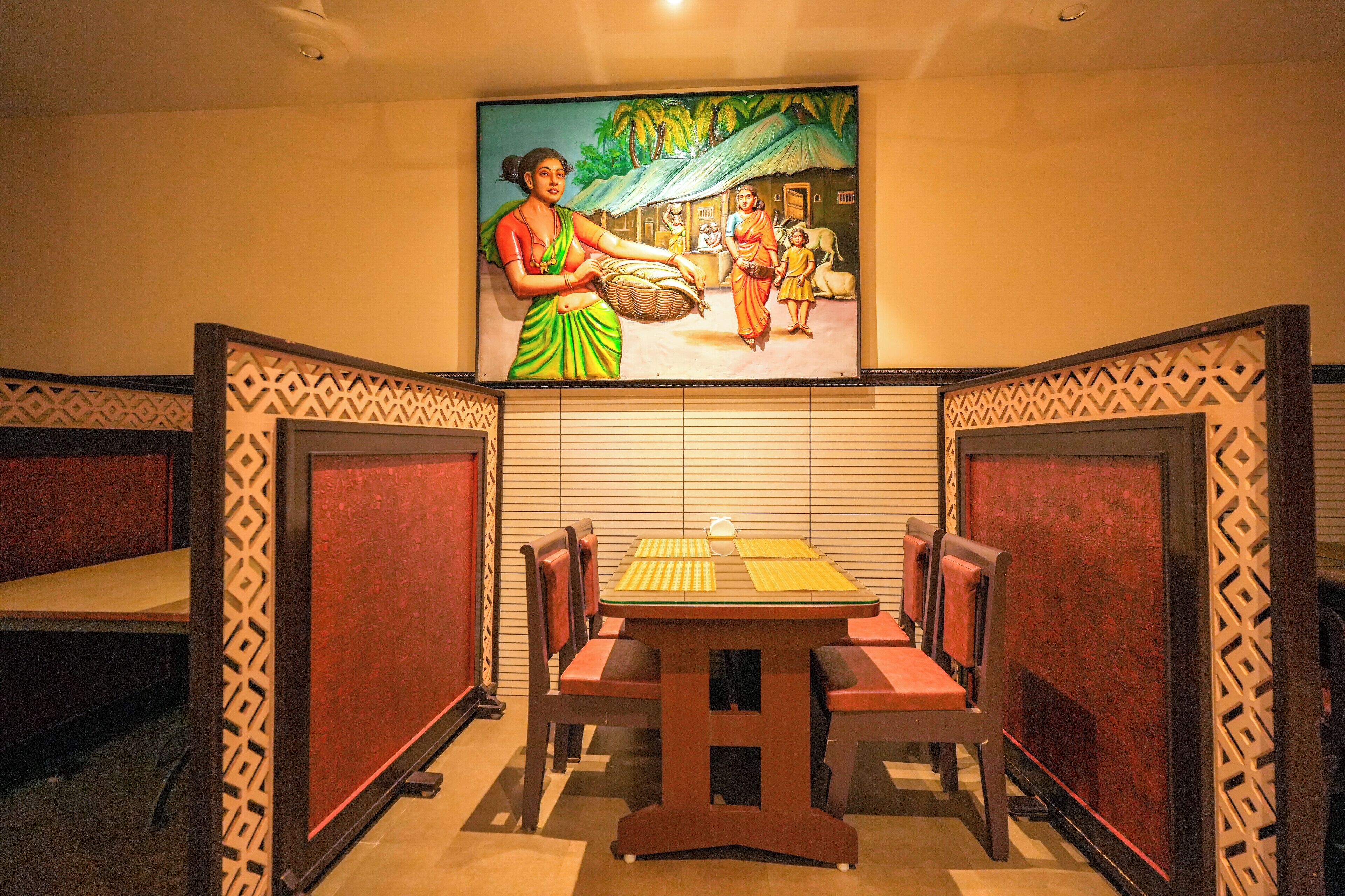 A dining area with a table and chairs, a painting on the wall, and patterned dividers.