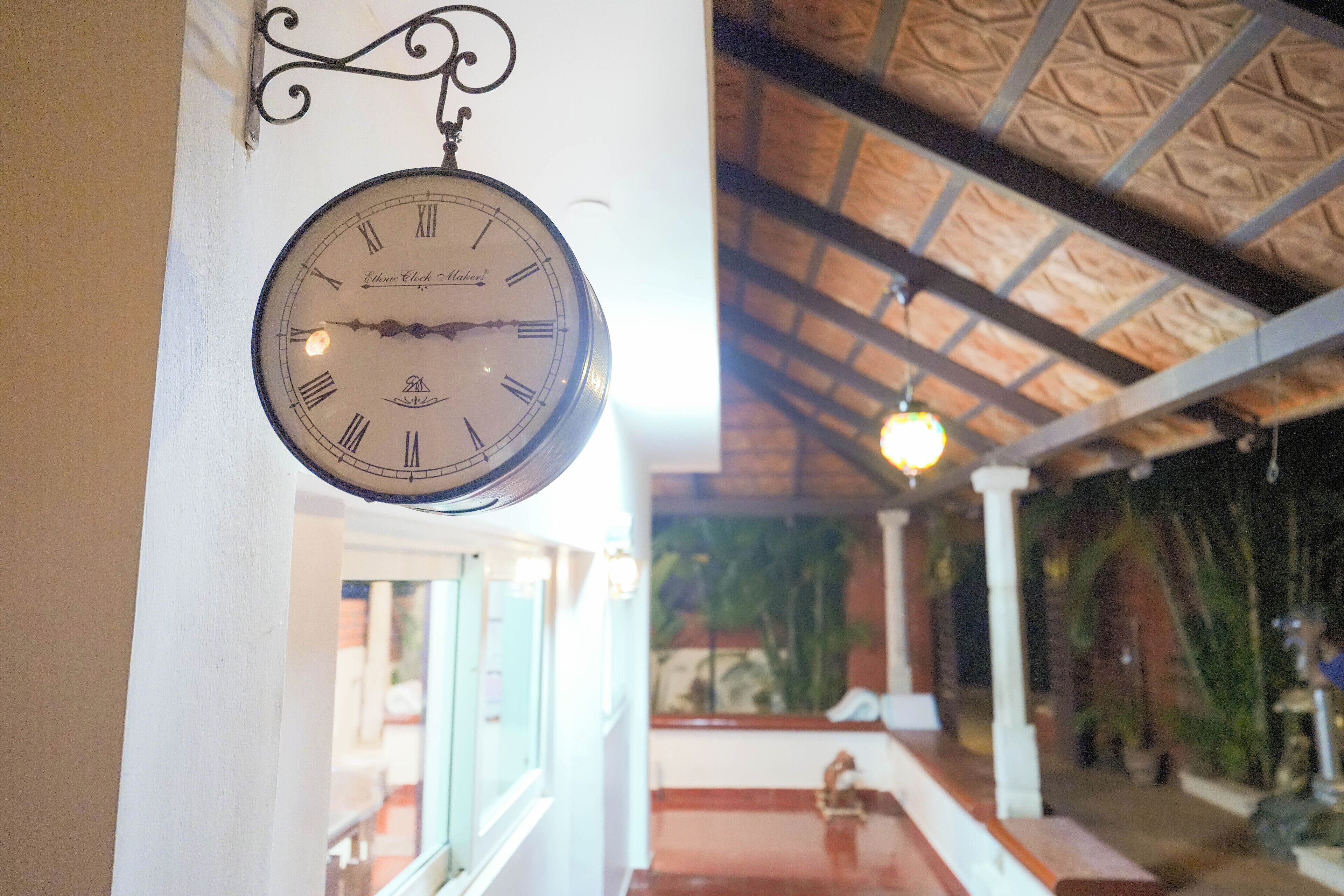 A clock with Roman numerals hanging on a white wall.