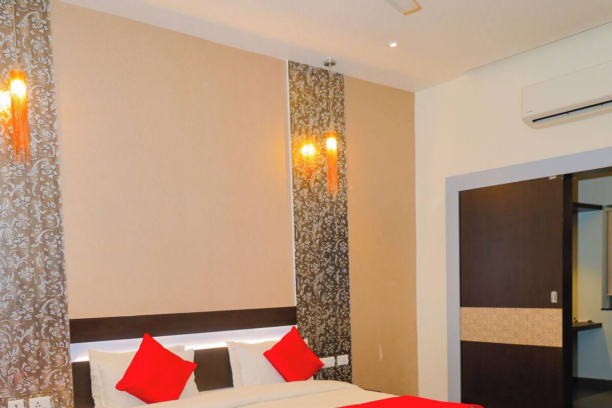 Une chambre d’hôtel avec un grand lit, un ventilateur de plafond et une table de chevet avec un téléphone.