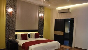A hotel room with a large bed, a nightstand, an air conditioning unit, and a door leading to another room. - Mount Retreat (Madurai)