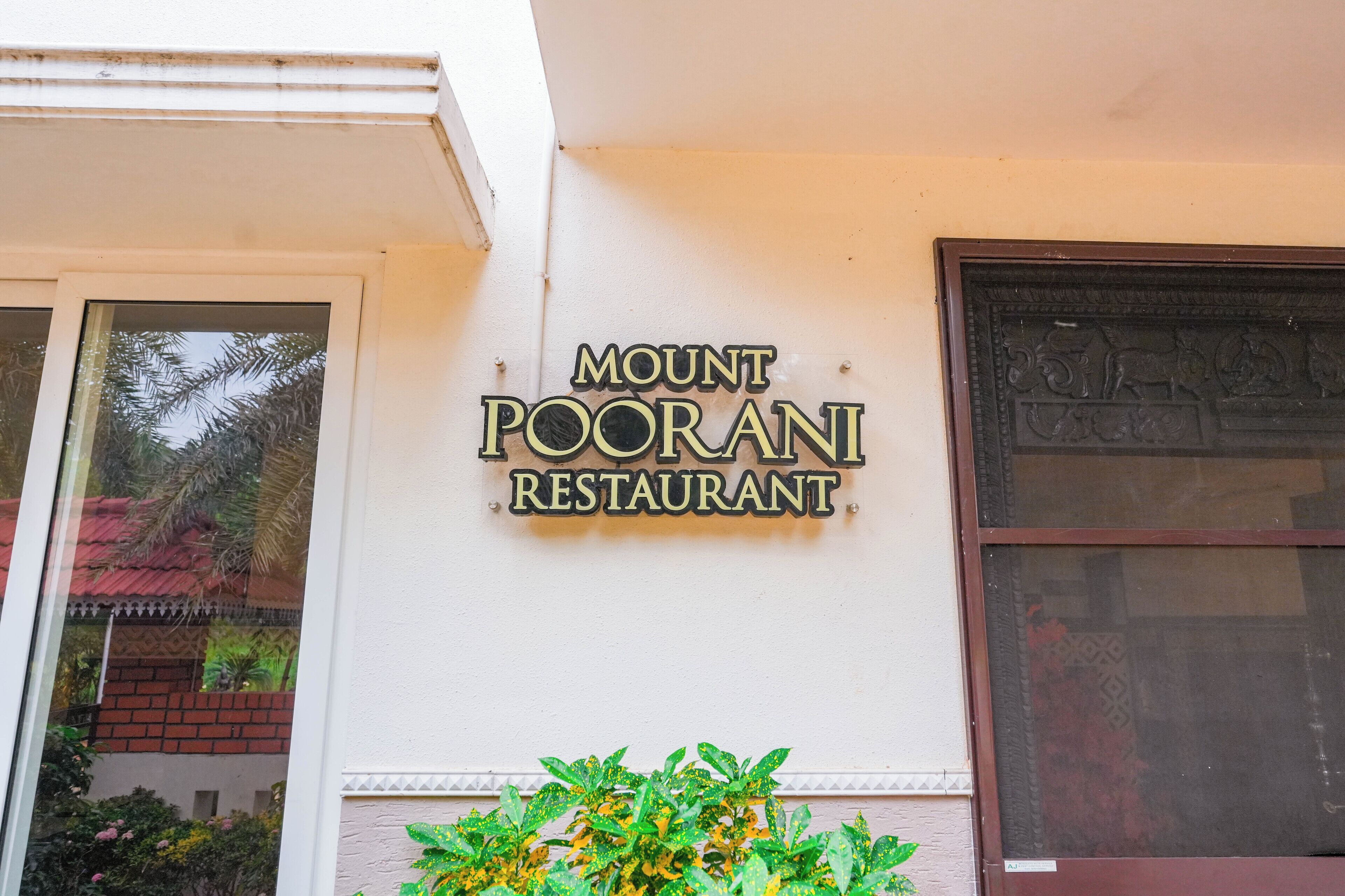 A sign for Mount Poorani Restaurant on a building's exterior wall.