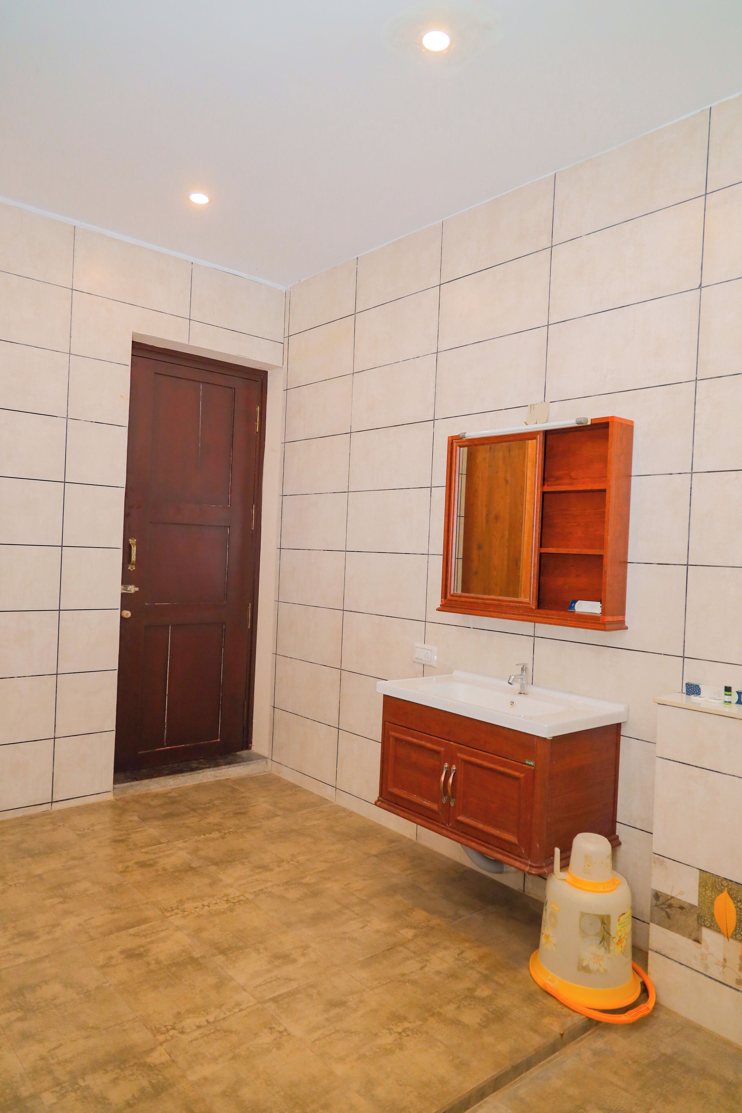 Un baño con puerta de madera, un lavamanos blanco, un armario para espejo y una zona de ducha.