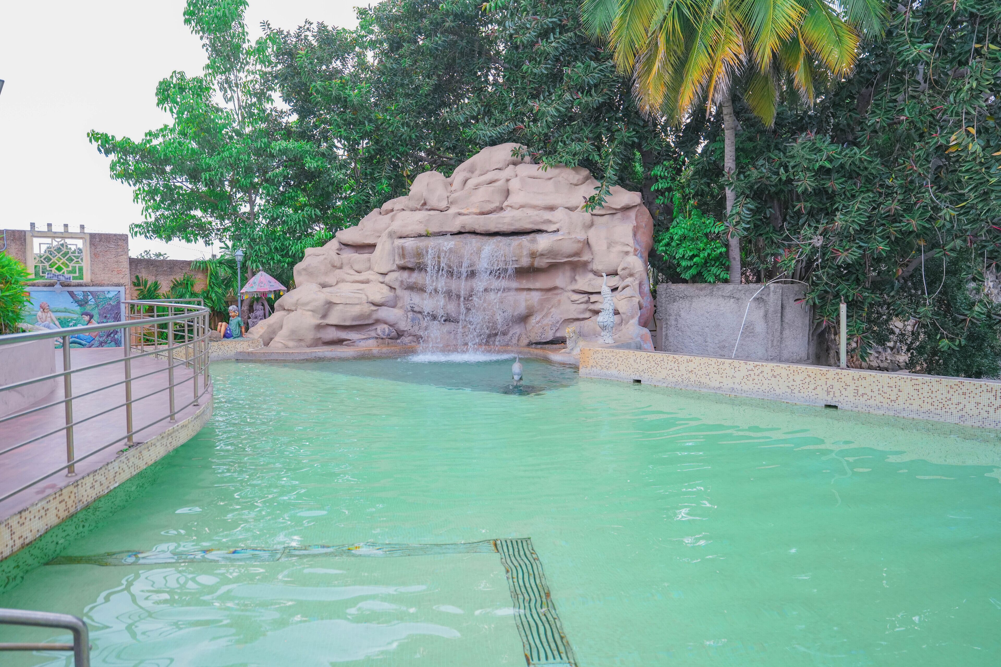 Ein Schwimmbecken mit Felsformation und Wasserfall.