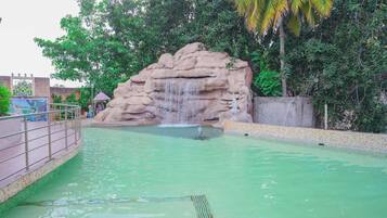 Ein Schwimmbecken mit Felsformation und Wasserfall.