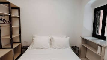 Un dormitorio moderno con una cama grande, un armario y una pequeña zona de estar.