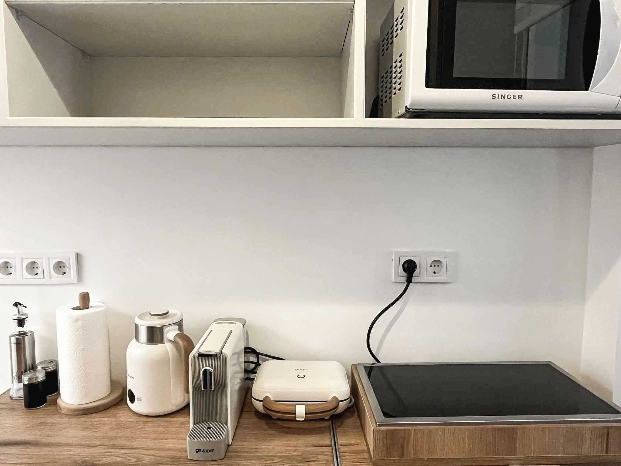 Eine Küche mit Mikrowelle, Toaster und weiteren Geräten auf einer Holzausziehtischplatte.