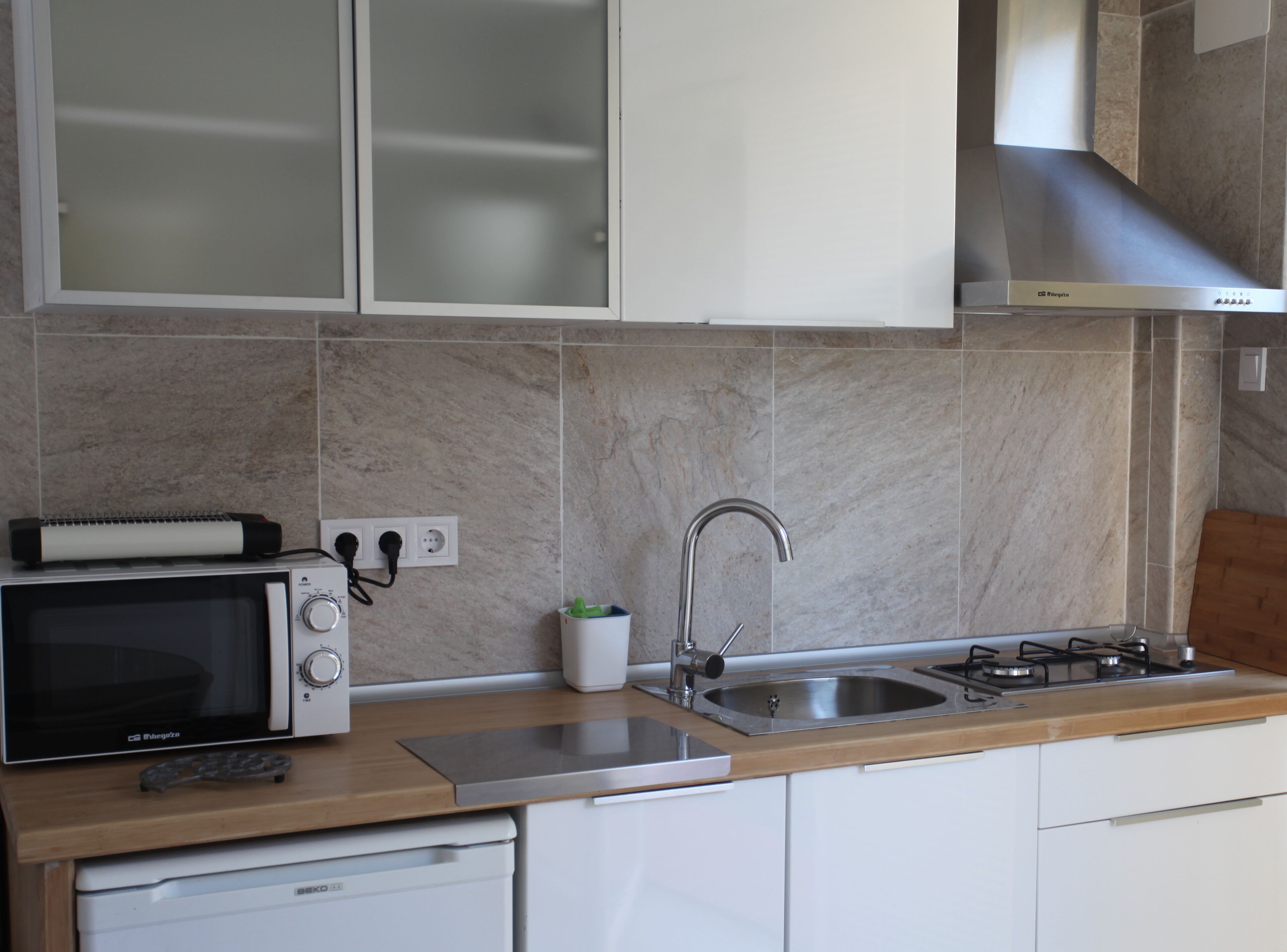 Una cocina equipada con microondas, tostadora, lavabo y estufa.