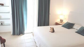 A hotel room with a bed, a nightstand with a lamp, a dresser, and a chair.