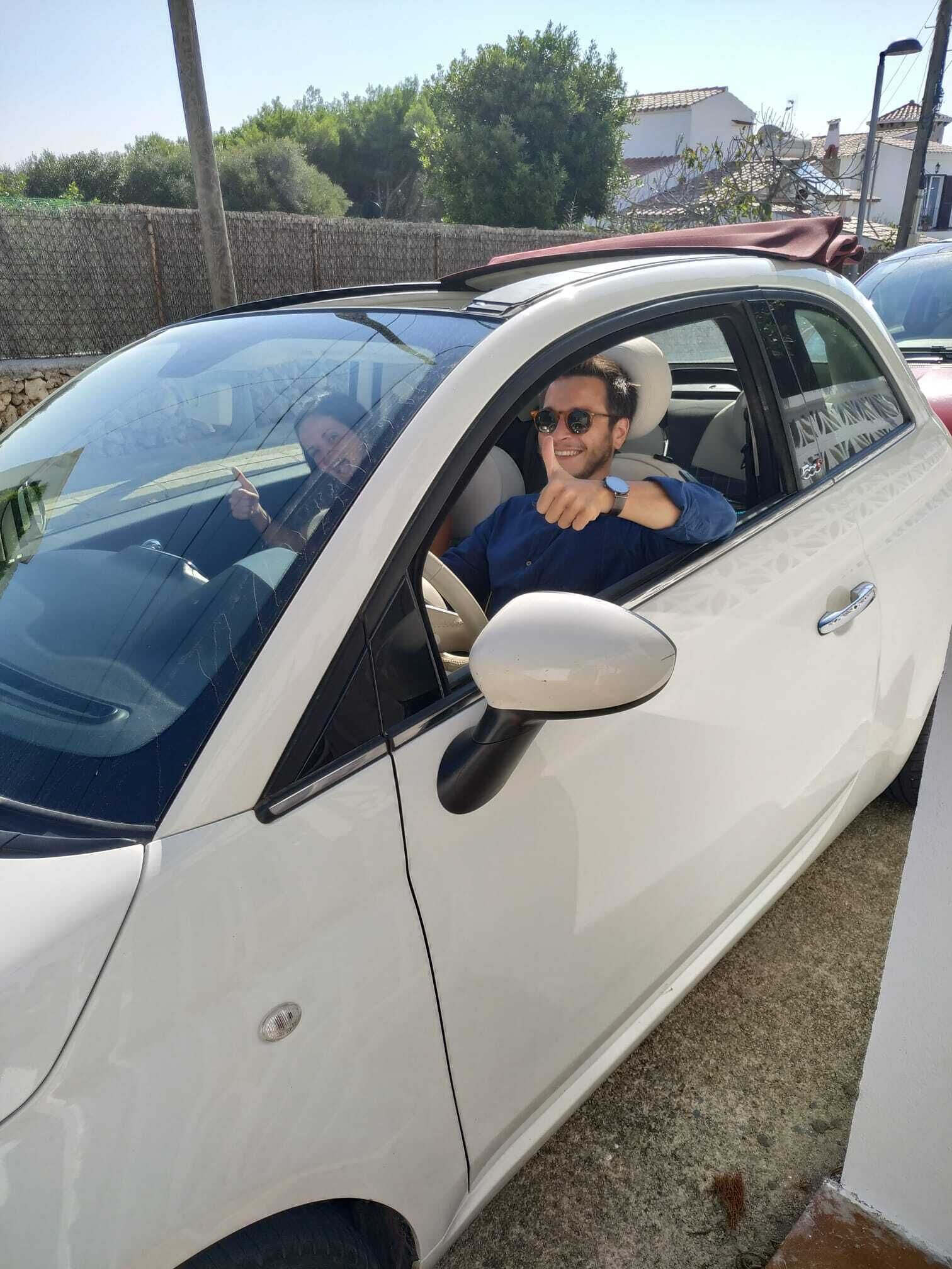 A white car parked outdoors with a person inside.