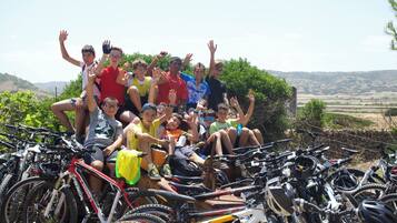 Un grupo de personas posando con bicicletas en un entorno exterior soleado.