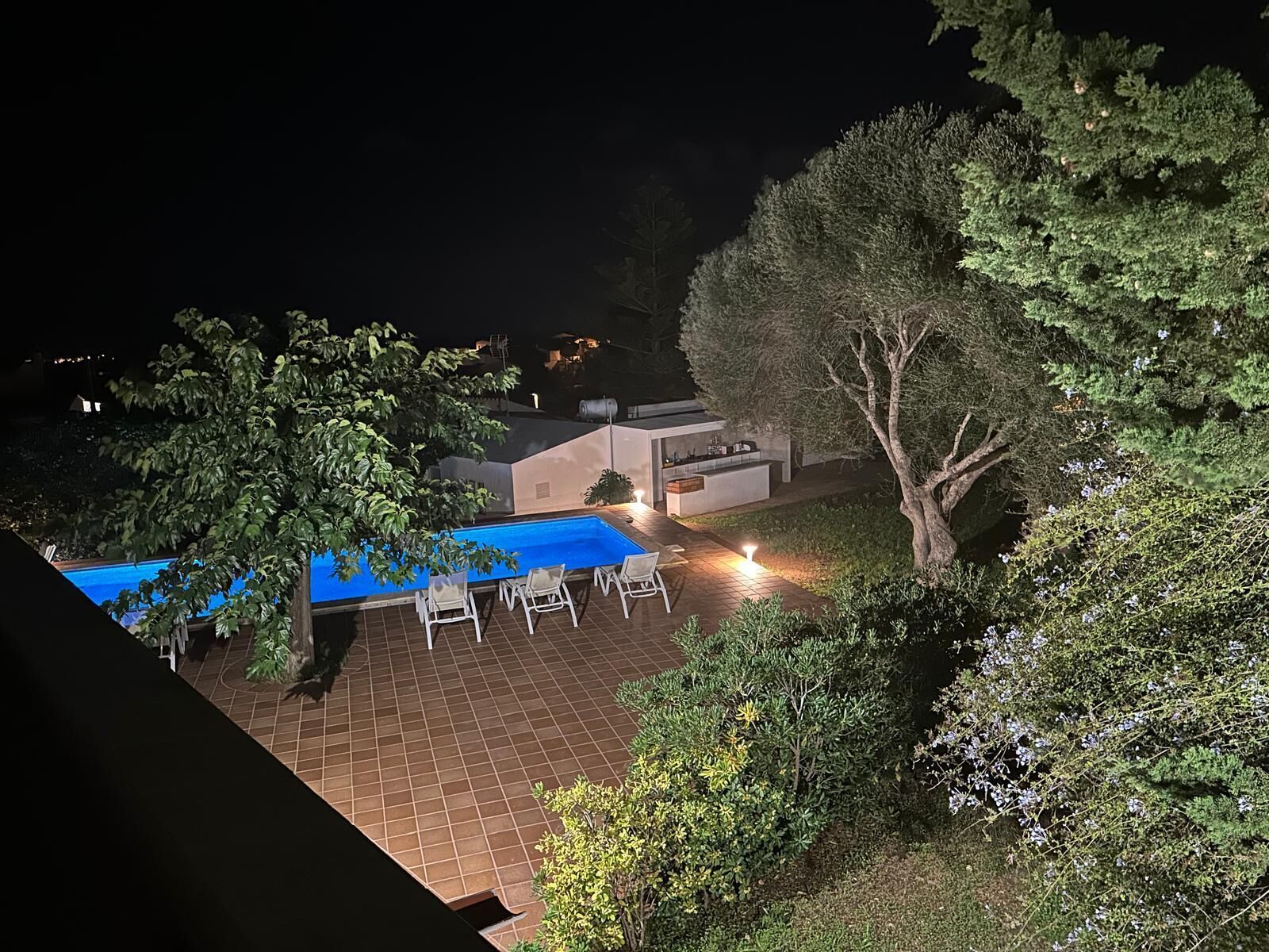 A rooftop pool area with a blue pool cover, outdoor seating, and a small bar area.