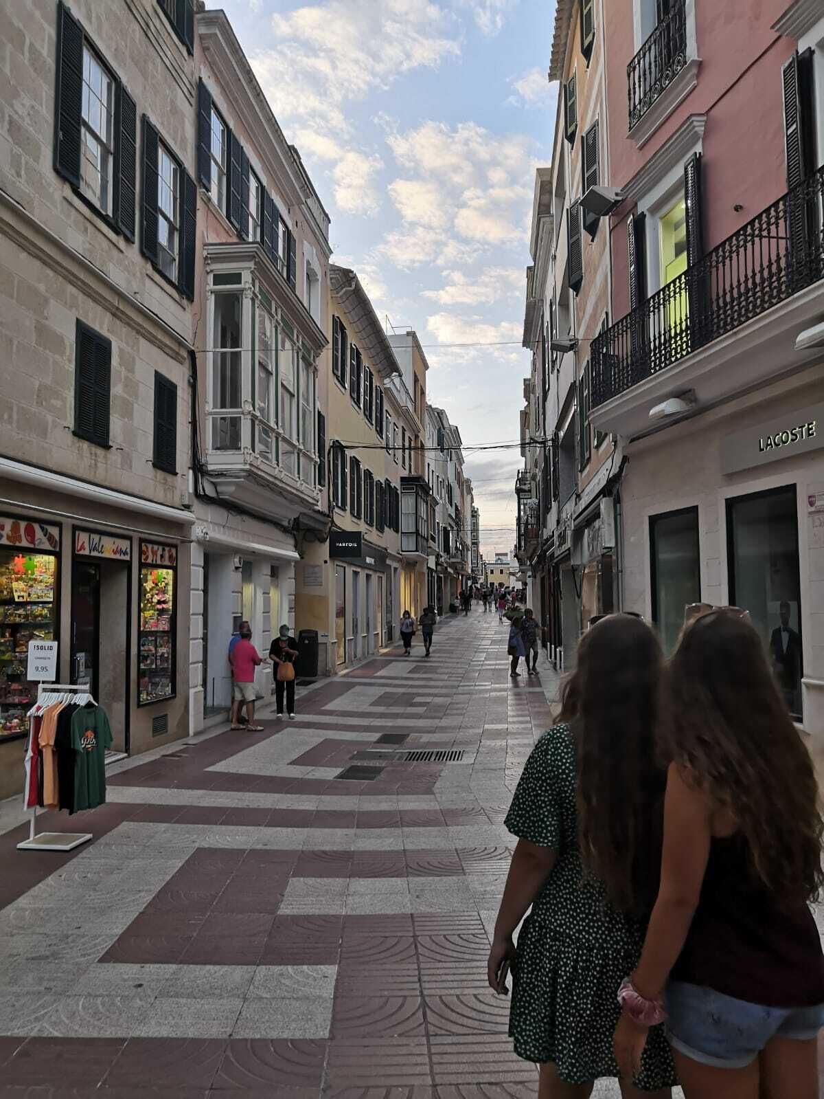 Una calle peatonal bordeada de tiendas y edificios, con una diversidad de escaparates y estilos arquitectónicos.