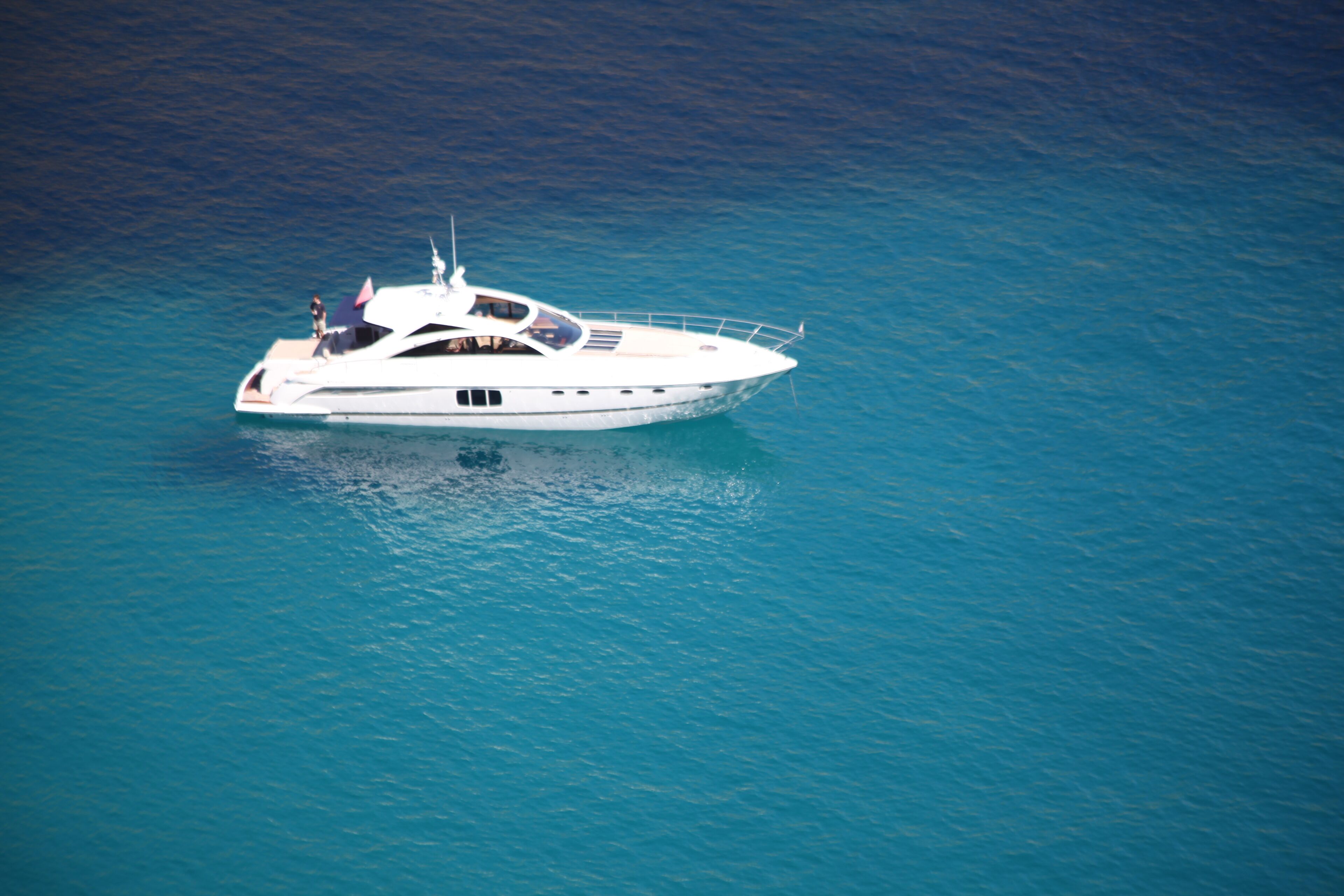 A large yacht with multiple decks and a flag, floating on calm blue waters.