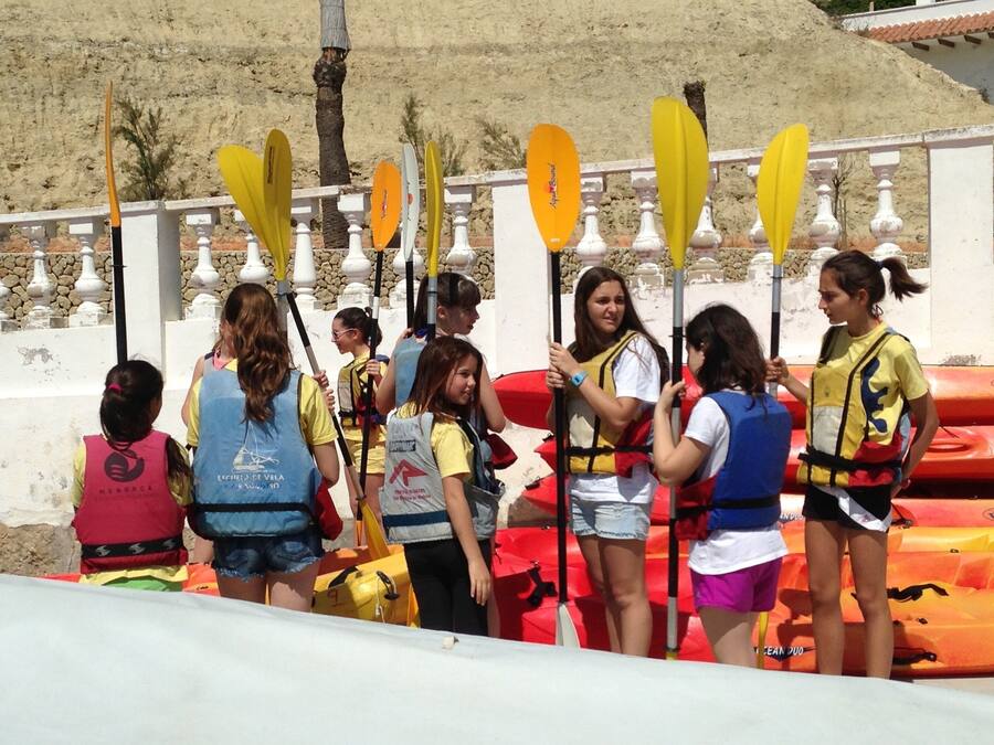 A group of people standing by a pool with paddleboards and kayaks.
