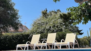 Een buitenzwembad en ligstoelen