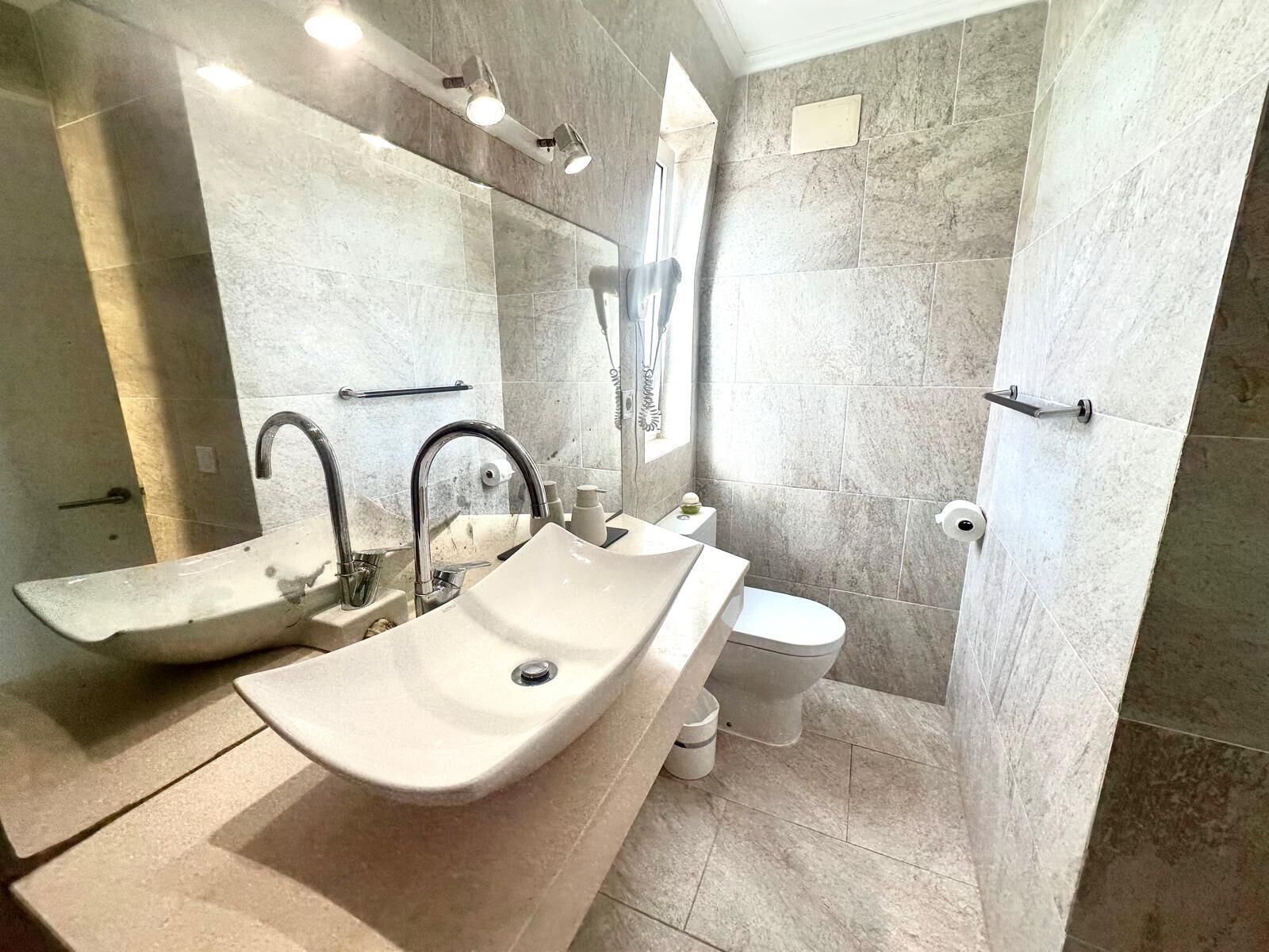 A modern bathroom with a large sink, a toilet, and a shower area.