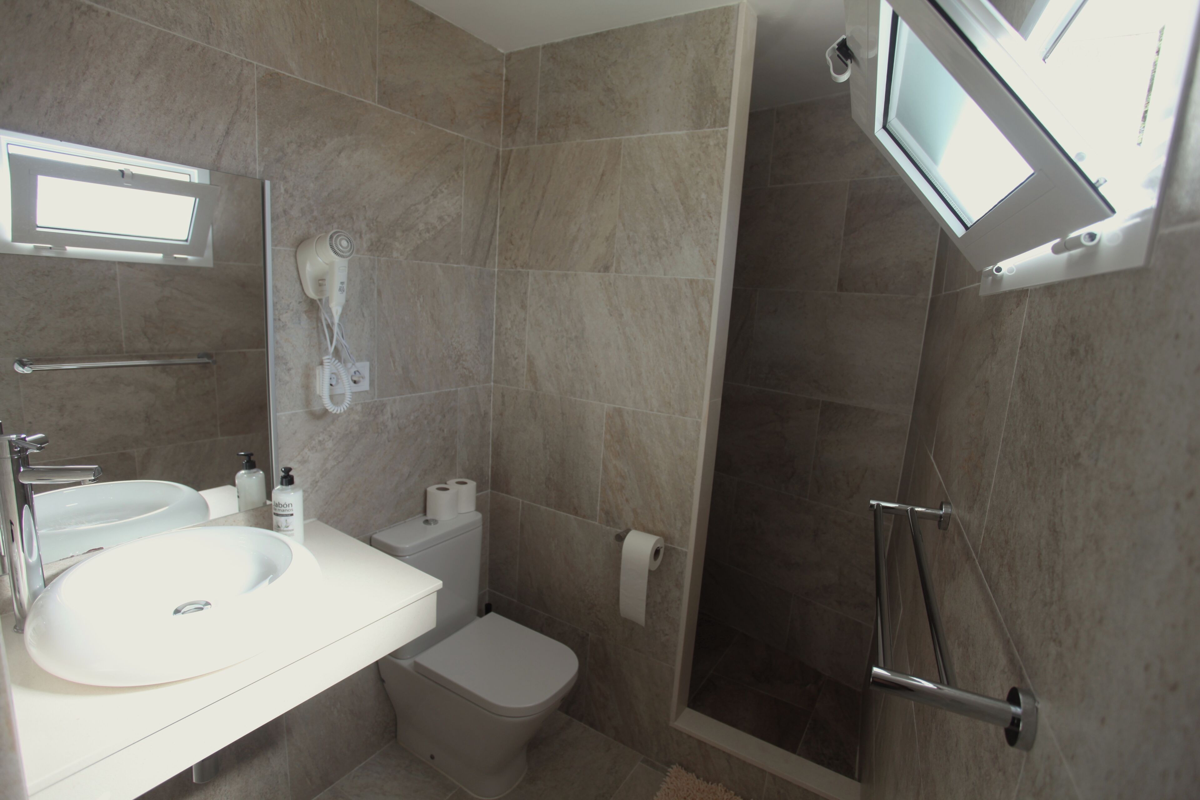 Een moderne badkamer met wastafel, toilet en douche.