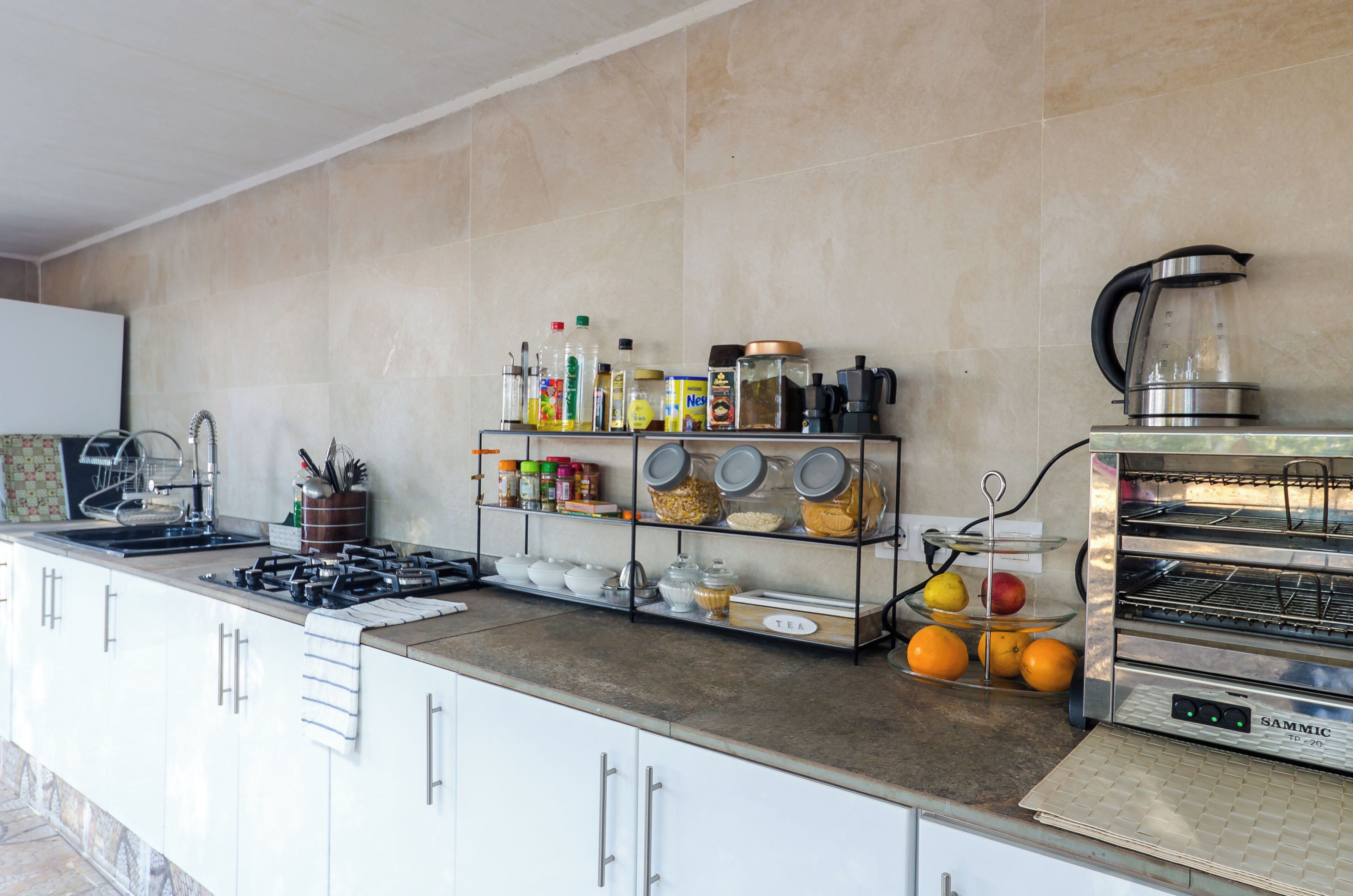 Una cucina moderna con piano cottura a gas, macchina del caffè, tostapane e una varietà di utensili ed elettrodomestici da cucina.