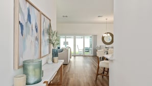 Un vaste espace de vie doté d’un plancher en bois, d’un canapé, d’une table à manger avec des chaises et d’une grande fenêtre offrant une vue sur l’extérieur.