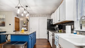 A modern kitchen with a blue island, white cabinets, and a stainless steel dishwasher.