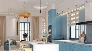 A modern kitchen with a central island, light blue cabinets, and a white countertop.