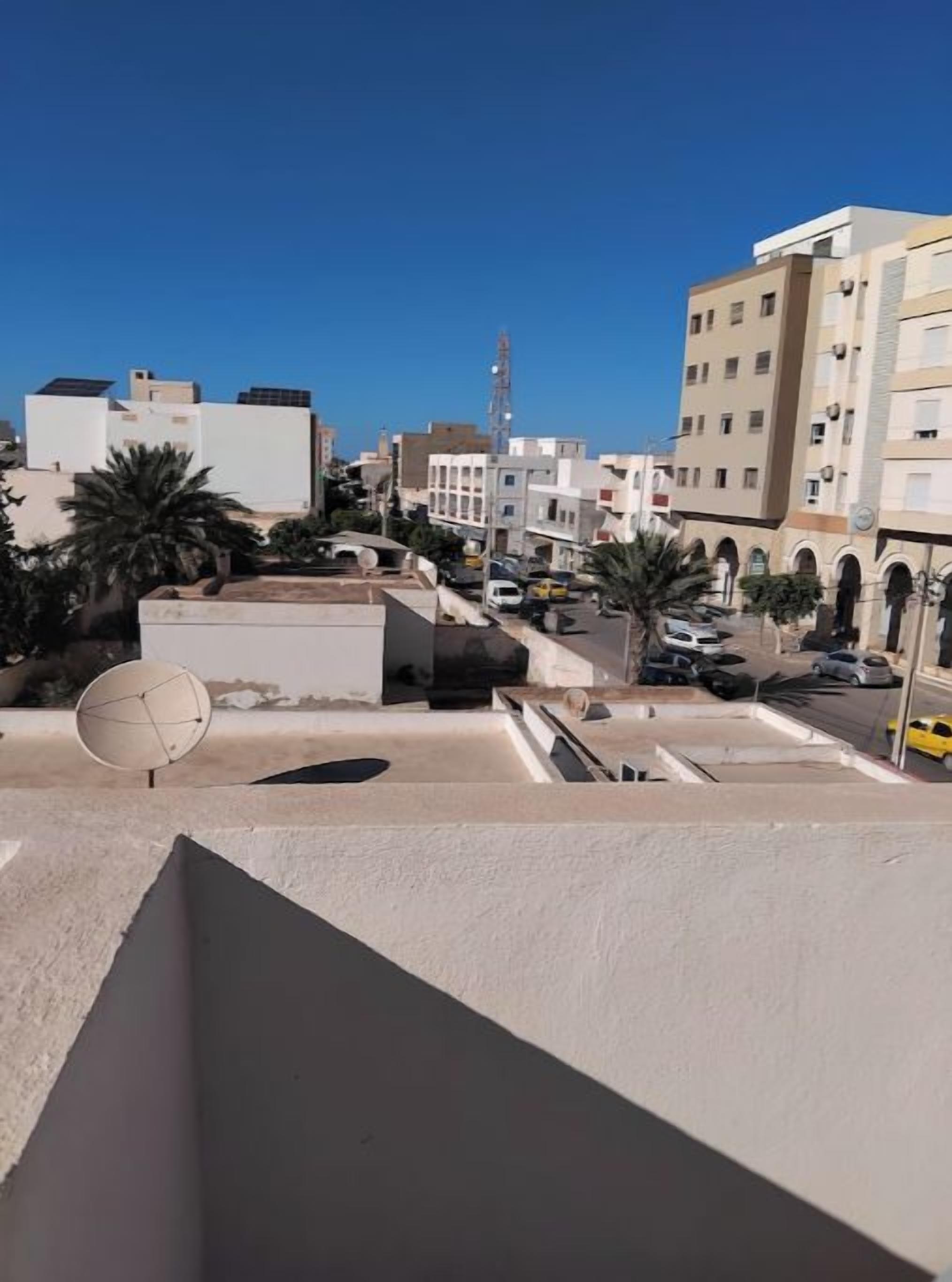 A rooftop terrace with a view of a cityscape, including buildings and a tower.