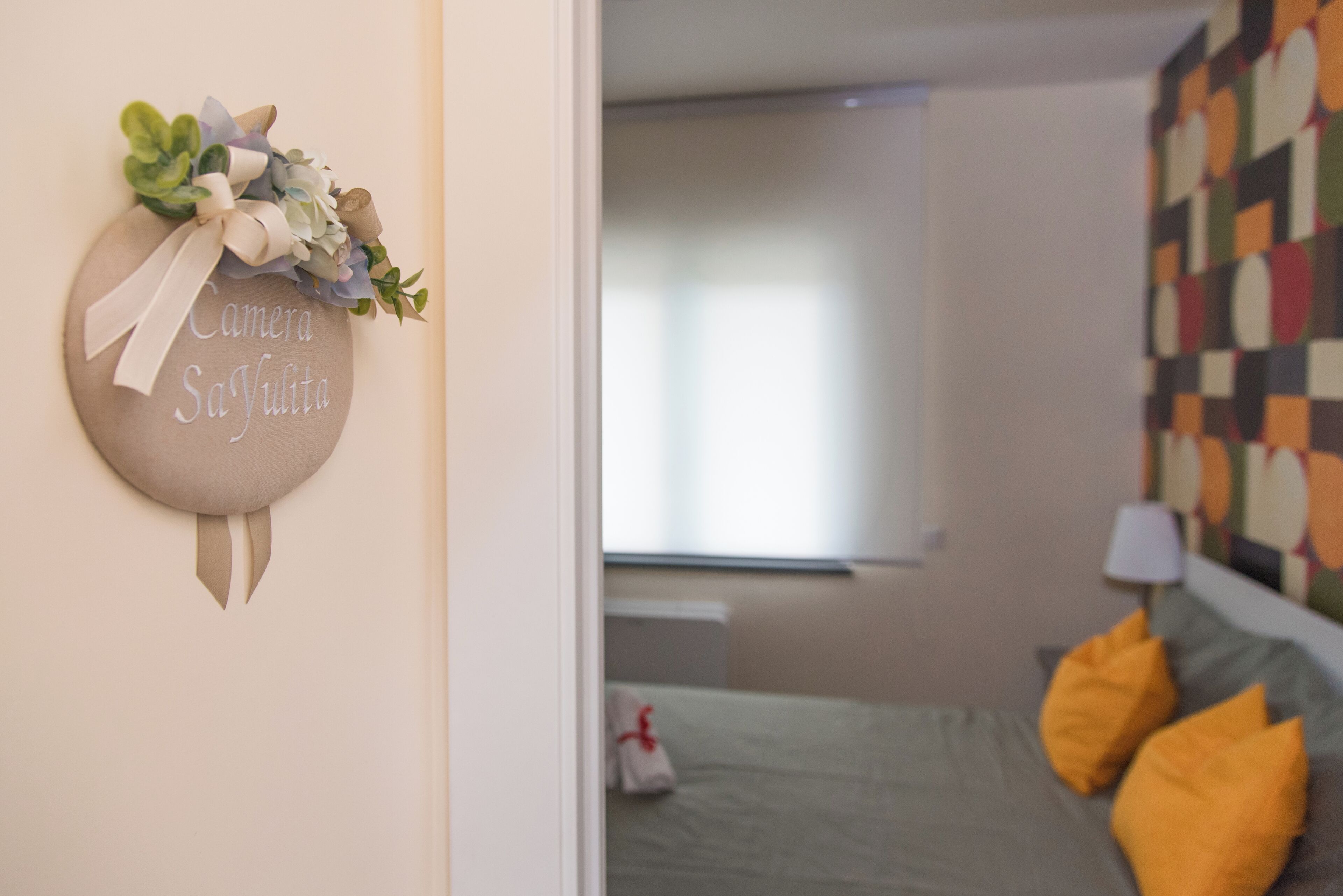 A bedroom with a bed, pillows, a bedside table, and a wall decoration.