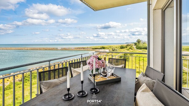 Een balkon met een eettafel, met uitzicht op de kust.