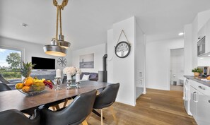 A modern kitchen with white cabinets, a wooden countertop, and a hanging light fixture.
